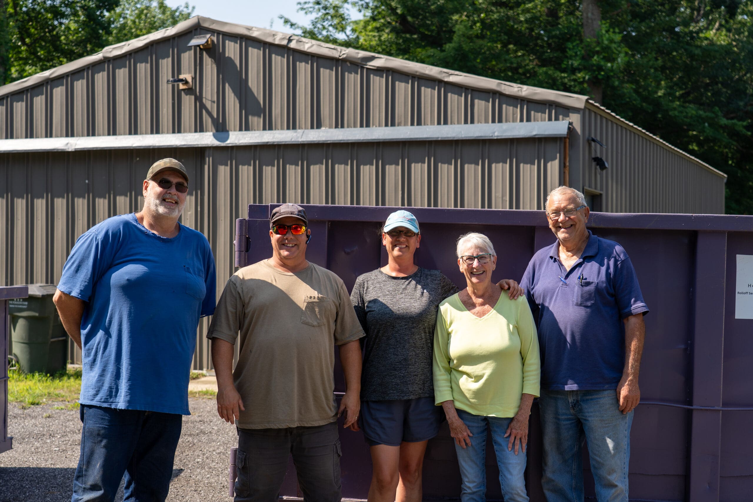 Harbor Country rolloff team photo in front of purple roll-off dumpster